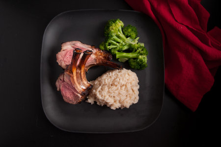 gourmet rack of lamb, chops with risotto and vegetables on a black backgroundの写真素材