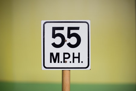 A closeup shot of a sign indicating the speed limit of 55 on a blurred backgroundの写真素材