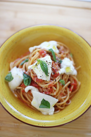 Spaghetti made with tomato sauce, buffala and fresh basil.の写真素材