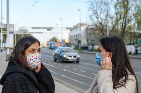 Female friends walking in city, wearing protective masks during corona virus epidemic.の写真素材