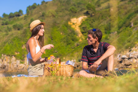 A young Caucasian couple on the picnic in the mountains by the sea enjoying the heat, summer lifestyleの写真素材