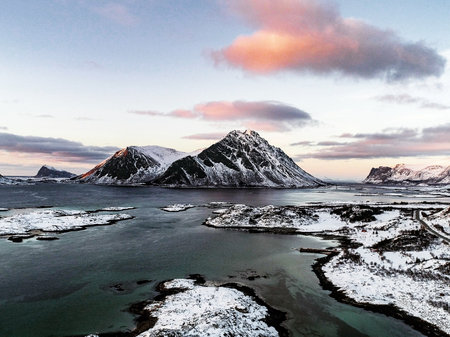 Aerial drone view of snowy mountains, colorful sunset sky, in Gimsoy, Lofoten, Norwayの写真素材