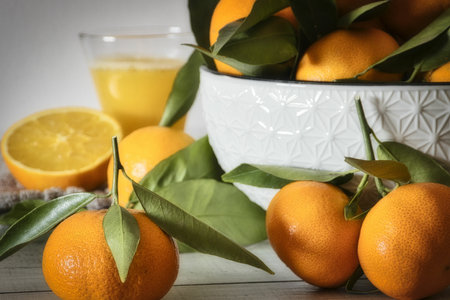 A bowl of fresh and ripe mandarines and a glass of juice on the kitchen tableの写真素材
