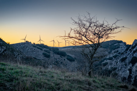 A landscape of windmills on rocky hills during the sunset in the eveningの写真素材