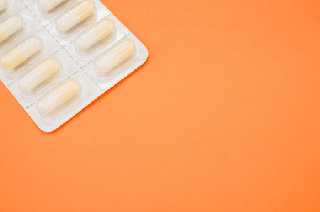 A high angle shot of a capsule tablet pack isolated on an orange backgroundの写真素材
