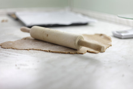 A closeup shot of a wood rolling pin and dough on the tableの写真素材