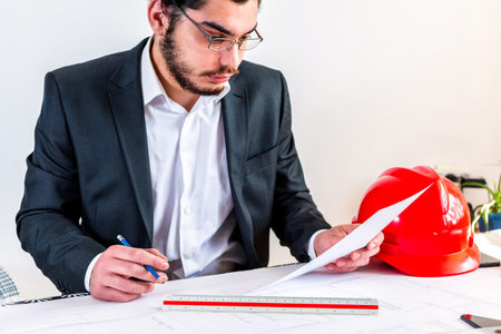 A Caucasian formal engineer focused on the plan while working in the officeの写真素材