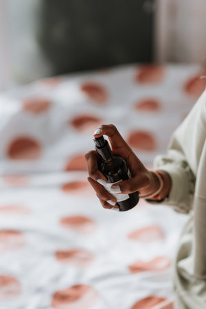 An African female spraying antibacterial sanitizing spray for clothes and linens before going to bedの写真素材