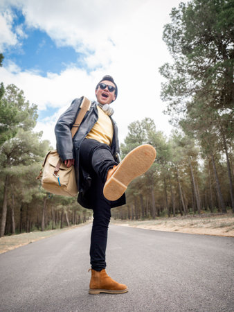 A shallow focus of a cool confident man with a bag standing on one leg on the roの写真素材
