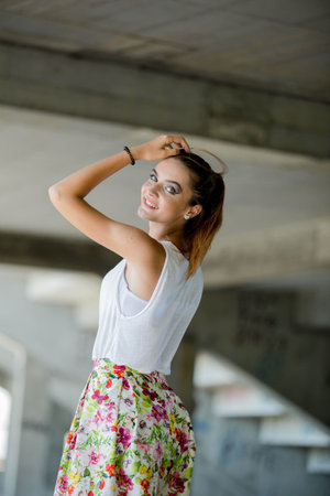 A shallow focus of a Caucasian female wearing a floral skirt with a shirt and posing in a parkの写真素材