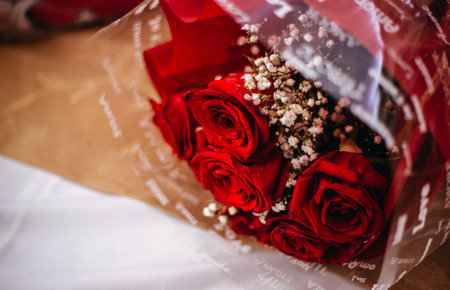 A beautiful bouquet with red roses wrapped in red paper and a transparent plastic sheetの写真素材
