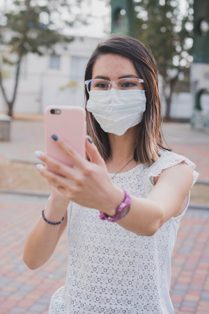 A Hispanic young woman making a video call with her phoneの写真素材