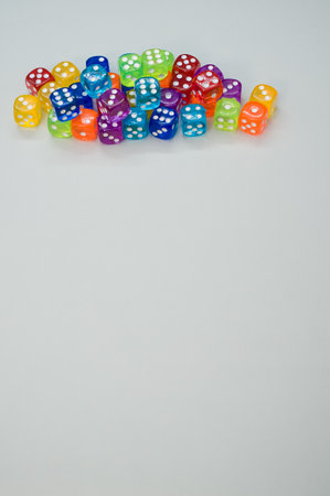 A vertical shot of colorful plastic dice on a gray surface with space for text