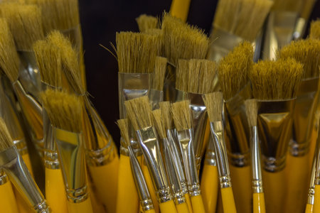 A high angle shot of various paintbrushes in different sizes, all with yellow wooden handlesの写真素材
