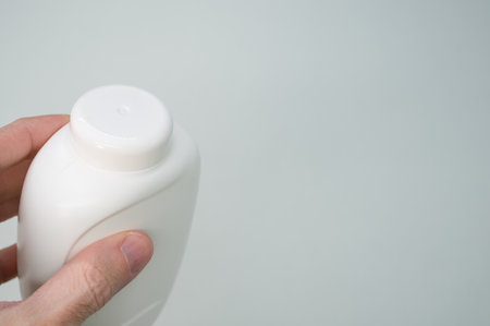 A hand holding white plastic bottle container isolated on light gray backgroundの写真素材