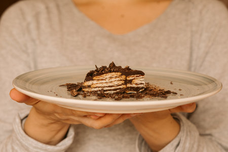 Man holding a piece of chocolate and biscuit cake. Homemade cake. Traditional birthday cake.の写真素材