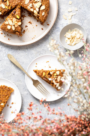 A top view of delicious homemade grated pie decorated with petals of almond and pistachioの写真素材