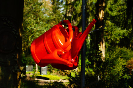 In Frankfurt's predominantly green main cemetery, the red watering cans inevitably attract attention. A strong contrast.の写真素材