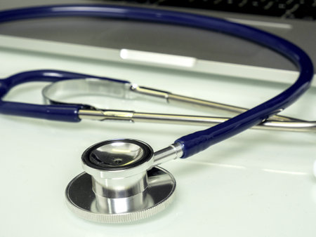 A closeup shot of a medical stethoscope next to a laptopの写真素材