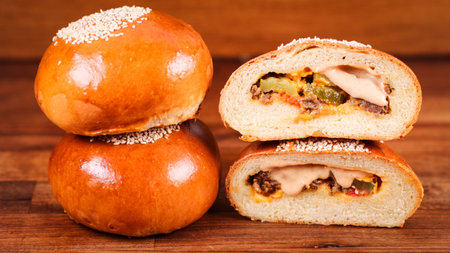 A closeup of freshly baked, delicious meat buns stacked on a wooden bordの写真素材