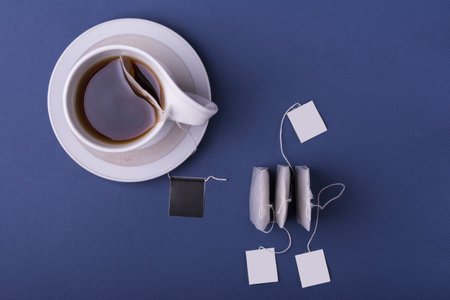 A top view shot of porcelain white cup tea with three teabags on dark blue backgroundの写真素材