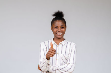 A smiling Nigerian woman celebrating success with thumbs upの写真素材