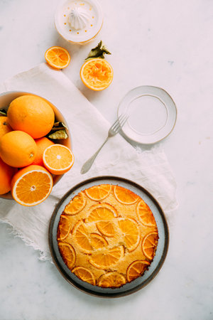 A top view of delicious homemade cake with sliced oranges on a white tableの写真素材