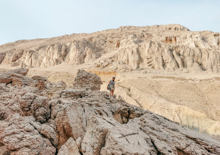 Young woman standing on rocky terrain in remote place in nature on sunny day in summer.の写真素材