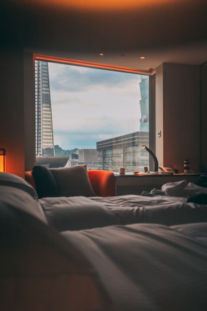 A vertical shot of a fancy bedroom overlooking the the buildings of the cityの写真素材