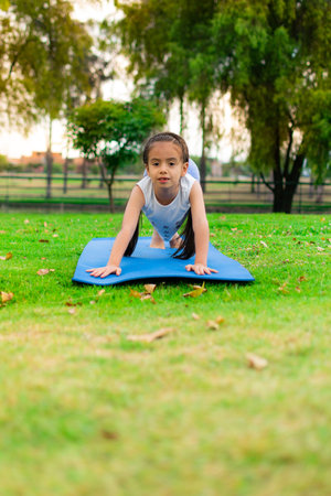 A vertical shot of a cute Latin girl practicing yoga in a parkの写真素材