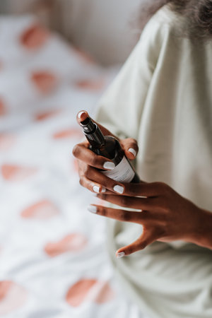 An African female spraying antibacterial sanitizing spray for clothes and linens before going to bedの写真素材