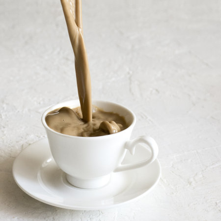 The moment of milk coffee being poured into a tiny cute cup.の写真素材