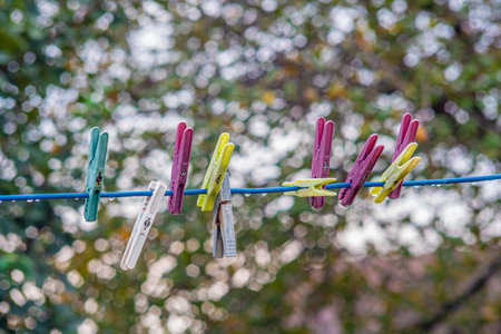 A selective focus shot of colorful plastic clothespins on a thin cableの写真素材