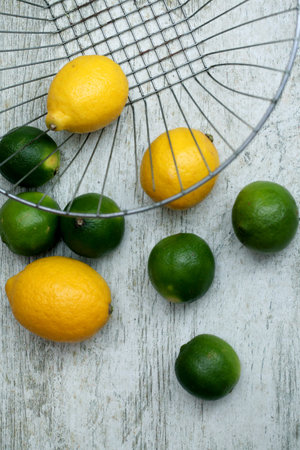A vertical shot of fresh lemons and limes on a wooden surfaceの写真素材