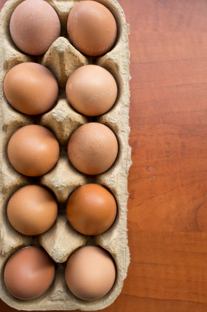 A top view of eggs in an egg carton on a wooden tableの写真素材
