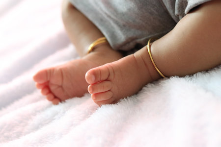 A closeup shot of feet of a kid with golden accessoriesの写真素材