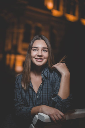 A portrait of a young Caucasian woman with green eyes wearing a blue flannel outdoors at nightの写真素材