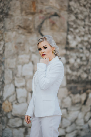 An elegant fashionable Caucasian female in a pretty white suit and pants posing for fashion photoshootの写真素材