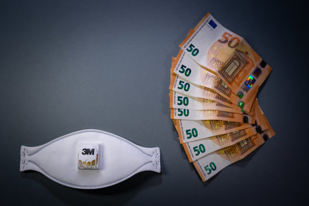 A top view of a protective mask and euro banknotes on a gray backgroundの写真素材