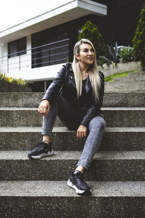A vertical shot of a blonde Hispanic female sitting in a parkの写真素材