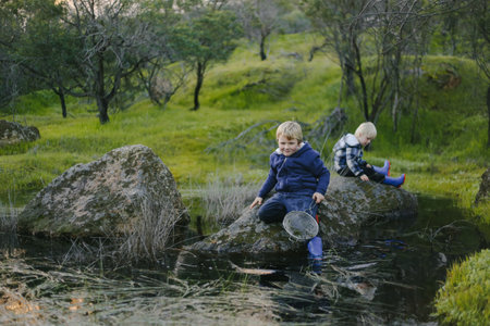 A cute little blonde kids sitting on a rock in a parkの写真素材