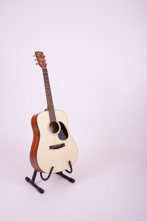 A vertical shot of a guitar on the stand in a white backgroundの写真素材
