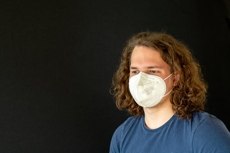 a middle eastern male portrait wearing a white face mask on a black background - new normalの写真素材