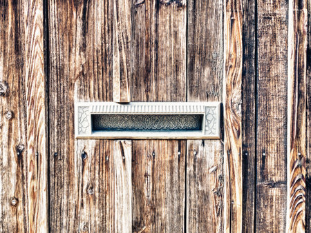 A closeup of an old traditional metallic mailbox in a wooden wallの写真素材