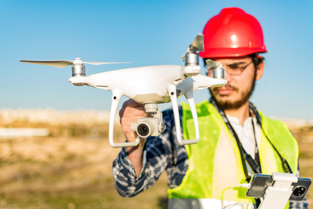 A male worker holding drones in the field - drone inspectionの写真素材