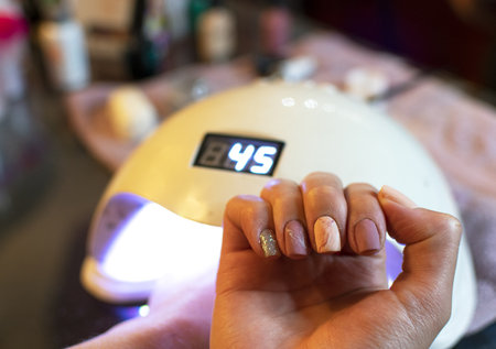 A selective focus shot of freshly painted nails out of the UV lightの写真素材