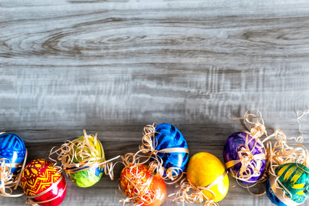A top view of colorful Easter Eggs on a wooden background with copy spaceの写真素材
