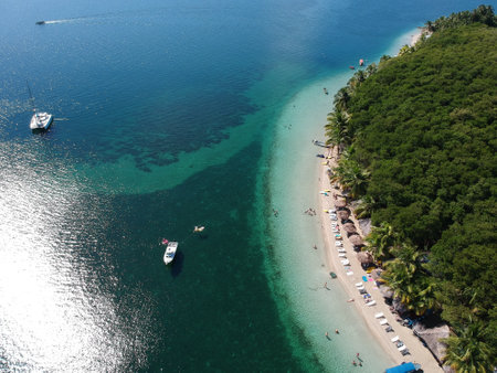 An aerial shot of an exotic beach resort with tiki huts and tourist boatsの写真素材