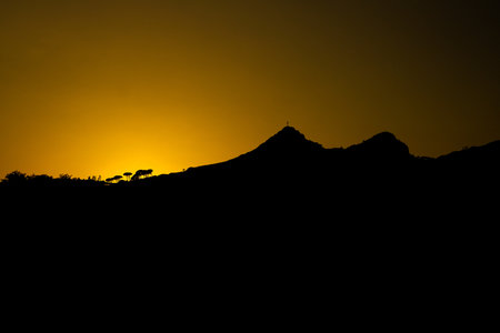 The silhouette of mountains against the orange sunset skyの写真素材