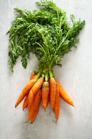 A top view of fresh carrots with a rope tied on a white tableの写真素材